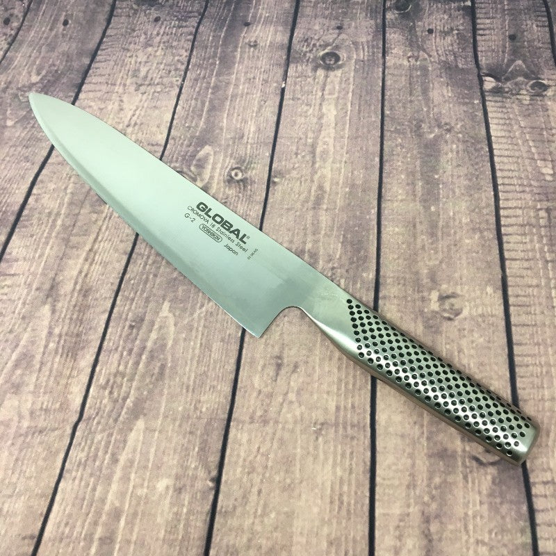 Chef profesional usando el cuchillo Global G-2 de 20 cm en cocina