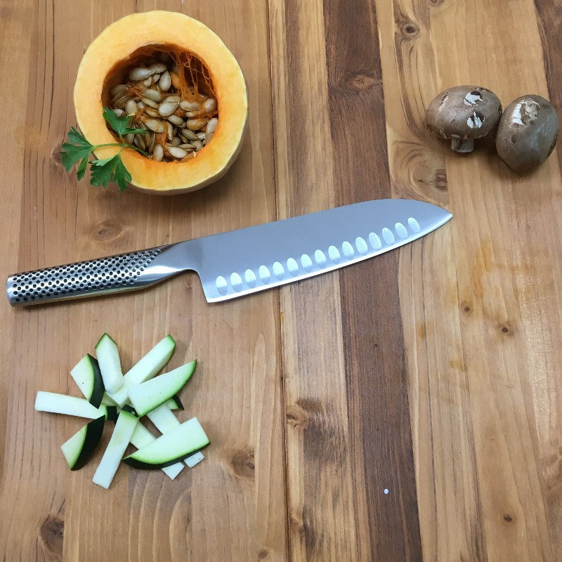 Cuchillo Global G-80 santoku sobre superficie de madera, detalle hoja alveolada